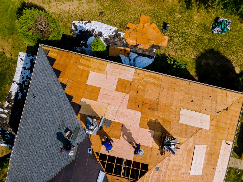 Aerial view of roof construction repairman on a residential apartment with new roof shingle being applied