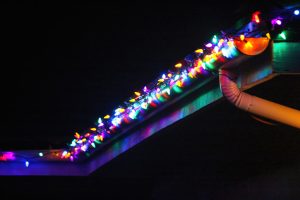 Photo of multi-colored Christmas lights hung up on the roof of a house at night.