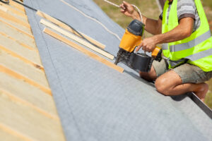 Roofer builder worker use automatic nailgun to attach roofing membrane