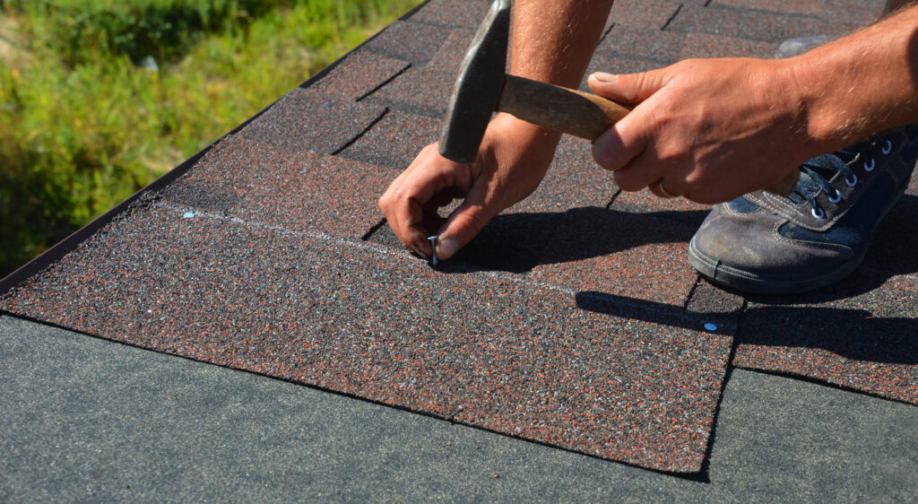 A close-up of asphalt shingles installation on the roof edge.